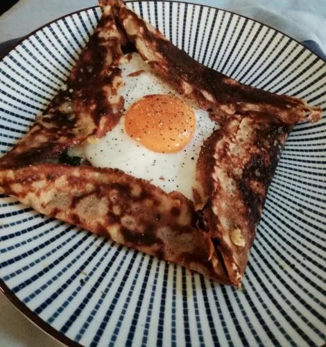 Buckwheat pancake with fried egg on a blue patterned plate