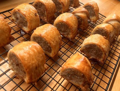 Rows of gluten-free sausage rolls on a cooling rack